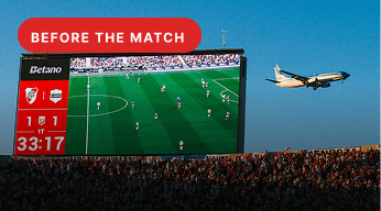 Before the match — stadium scoreboard and incoming flight