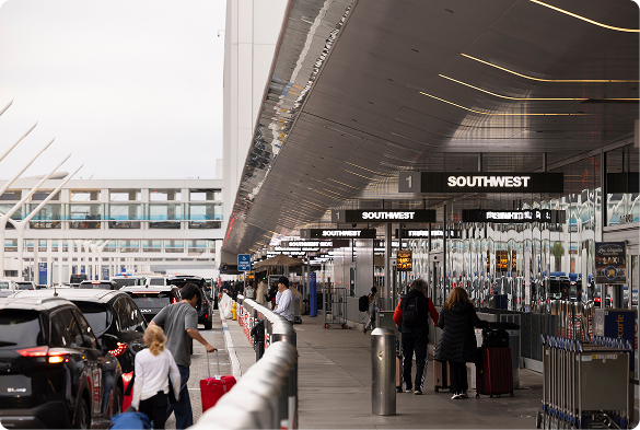 Passengers and rideshare vehicles outside LAX terminal